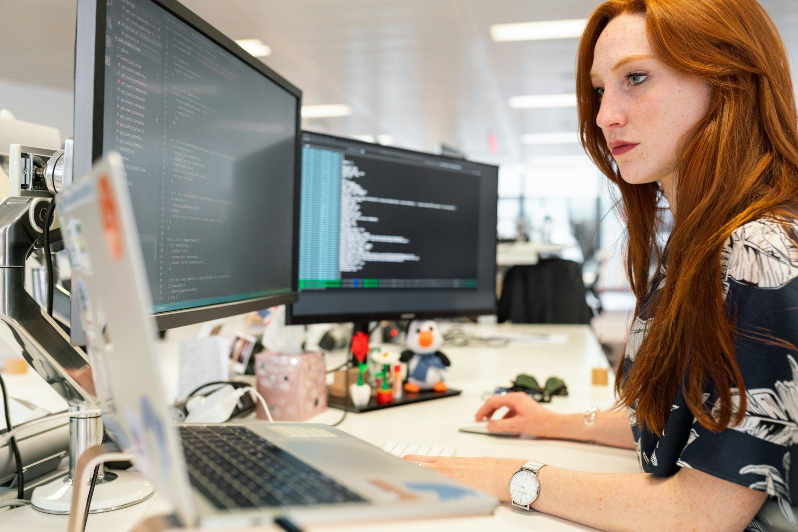 A software developer working at her monitors